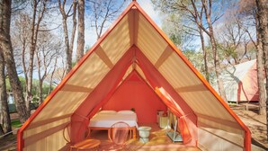A triangular tent with a bed, a chair, and a small table. - LAVITA Camp - Cagliari Villasimius (Quartu Sant'Elena)