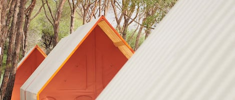 A row of simple, rectangular, tent-like structures with a single chair visible inside one.