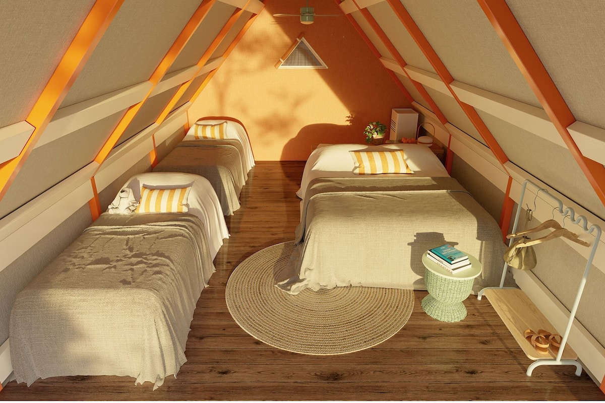 A cozy, triangular tent-style room with three beds, a woven rug, and a small table with books and a plant.