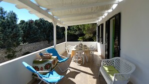 Eine überdachte Terrasse im Freien mit Esstisch, Stühlen und einer Sitzecke.