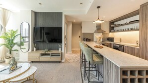 Een moderne keuken met een marmeren aanrechtblad, barstoelen en inbouwapparatuur.