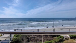 A beach with a clear sky, waves, and people walking along the shore. - Lagoon Beach Escape with Breathtaking Views (Cape Town)