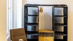 Una habitación con una mesa de comedor de madera, una estantería metálica negra y un pequeño armario de madera.