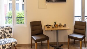 A room with two leather chairs, a small table with a TV mounted above, and a window with a view of greenery. - Charming modern apartment in a quiet Provencal house in Eyragues Alpilles (Eyragues)