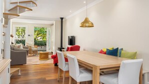 A modern dining area with a wooden table and white chairs, a red sofa, and a large pendant light.
