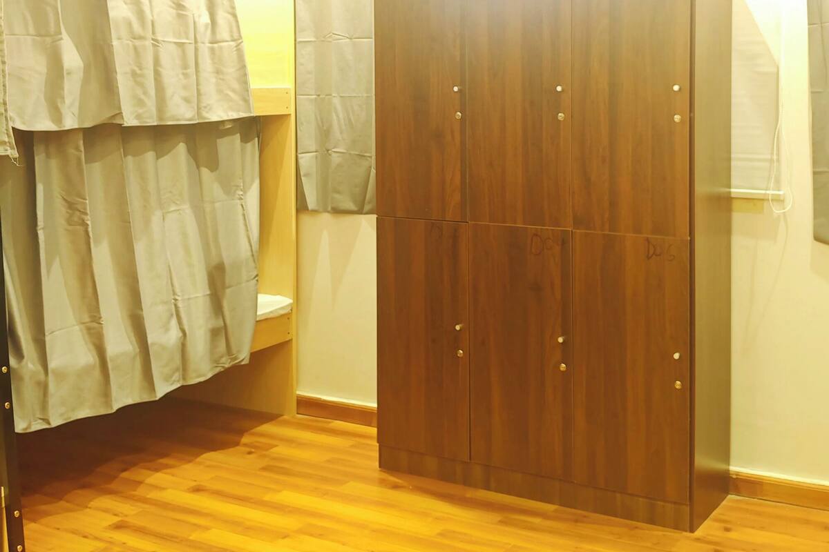 Quarto com guarda-roupa de madeira, sanita e cortina de chuveiro.