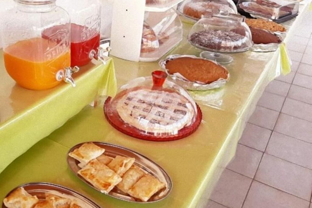 A buffet table with various food items including pies, pastries, and a drink dispenser.