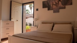 Um quarto com cama, cômoda, mesa de cabeceira, abajur e um quadro na parede.