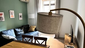 Ein gemütliches Wohnzimmer mit einer Couch, einem Esstisch mit Stühlen, einer Lampe und Kunstwerken an der Wand.