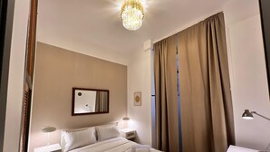 Ein Hotelzimmer mit Bett, Nachttischlampen, Schreibtisch, Spiegel und einer Chandelier.