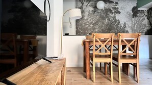 Ein Essbereich mit einem Holztisch, Stühlen, einer modernen Lampe und einem wandmontierten Spiegel.