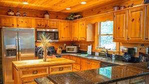 A kitchen with wooden cabinets, a granite countertop, stainless steel appliances, and a central island with a vase.