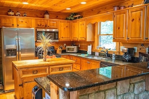 A kitchen with wooden cabinets, a granite countertop, stainless steel appliances, and a central island with a vase.