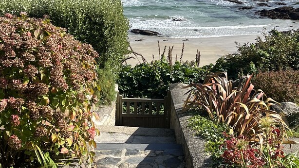 Eine Steintreppe führt zu einem Strand mit Blick auf das Meer.