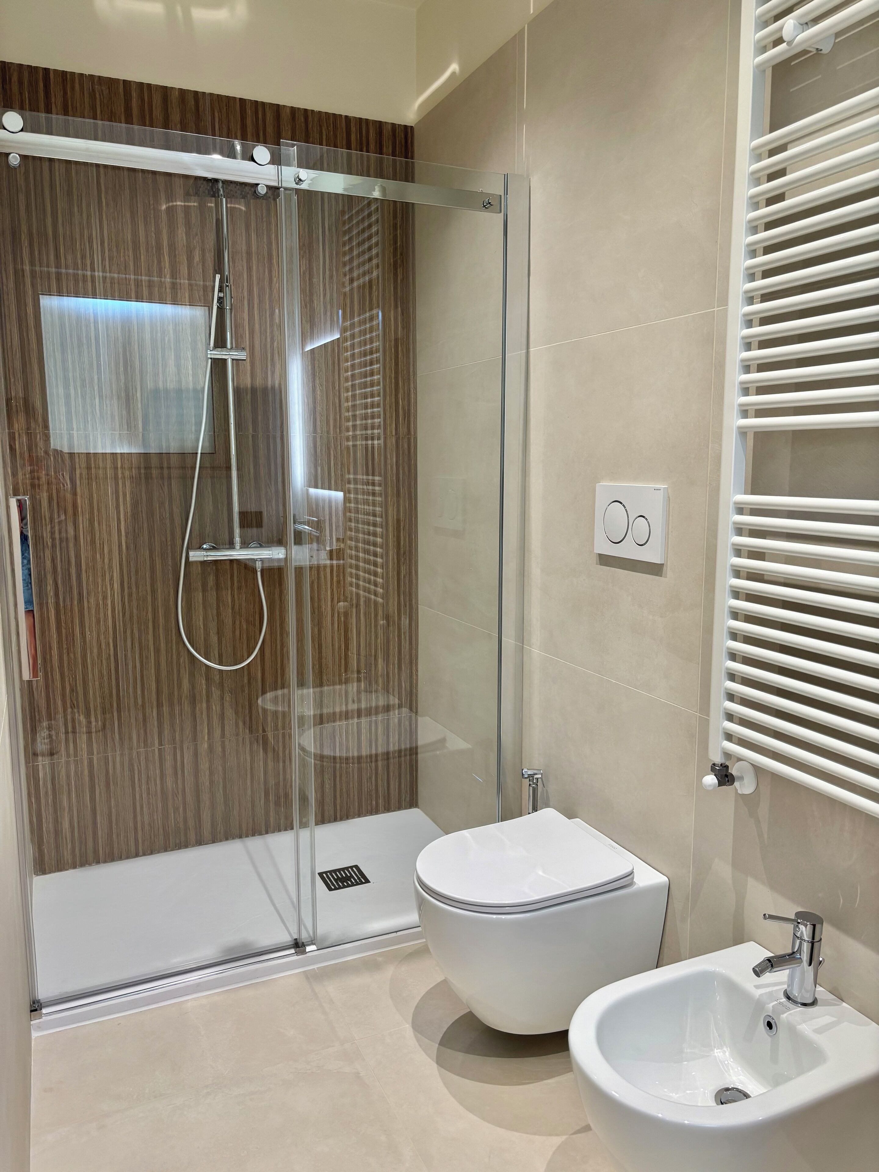 Un baño moderno con ducha envuelta en vidrio, inodoro y bidé.