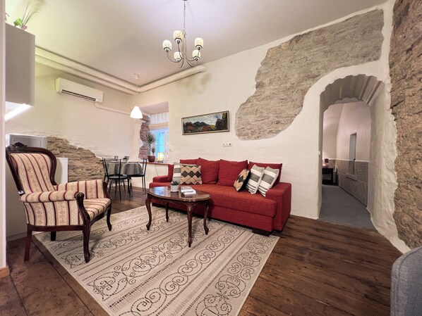 A living room with a red sofa, striped armchair, and patterned rug. - 1-bedroom Old Town apartment (Tallinn)