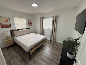 Cozy retreat with a single bed, bedside table, and potted plant.