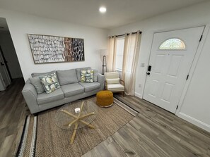 Relax in this stylish living room with a sofa, coffee table, and ottoman, surrounded by a contemporary painting and a minimalist design.