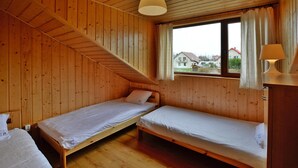 Eine Holzhütte mit zwei Etagenbetten, einer Treppe, einem Fenster mit Vorhängen und einer Lampe auf einem Nachttisch.