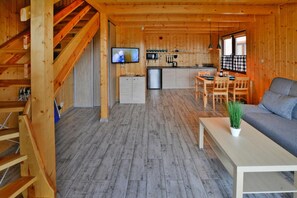 A wooden cabin interior with a dining area, kitchen, and living room. - Holiday Home in Sianozety Near Beach (Ustronie Morskie)
