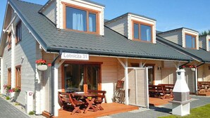 Ein zweistöckiges Gebäude mit überdachter Terrasse, einem Schild mit der Aufschrift 'Lotnicia 31' und Sitzgelegenheiten im Freien.