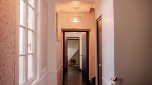 A hallway with a wooden floor, a patterned wall, a door with a lock, and a hanging light fixture. - Frida KAHLO family room in the Château outbuilding overlooking the Loire River (Brissac-Loire-Aubance)