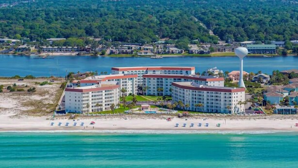 Un hotel frente al mar con varias edificaciones, una playa y una torre de agua.