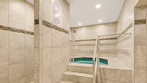 Un área de spa con piscina, paredes azulejadas y un cartel con las normas del spa.
