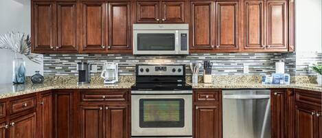 A kitchen with wooden cabinets, a stainless steel microwave, stove, and dishwasher.
