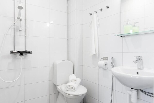 A modern bathroom with a toilet, shower, and sink. - Oma Hotelli (Ylojarvi)