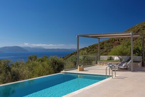 A swimming pool with a view of the sea, a covered seating area, and lounge chairs. - Efxenia Villas-Villa Luna (Lefkada)