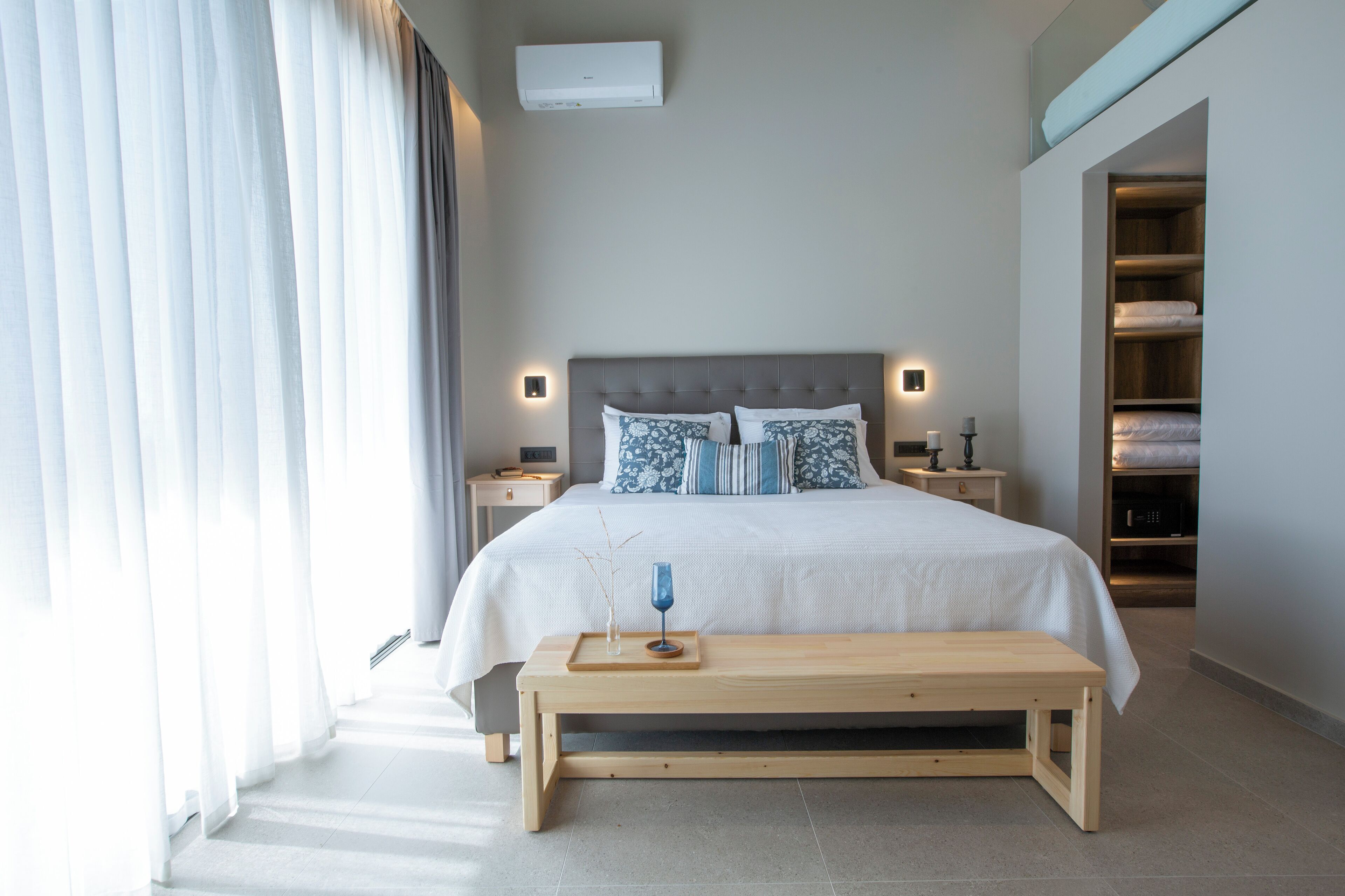 Un dormitorio moderno con una cama grande, mesitas de noche, un banco y un armario.
