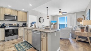 A modern kitchen with a central island, built-in appliances, and a view to the outside.