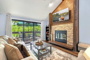 A living room with a fireplace, a sofa, a coffee table, and a TV mounted on the wall. - Ozark Escape: Resort-Style Fun (Osage Beach)