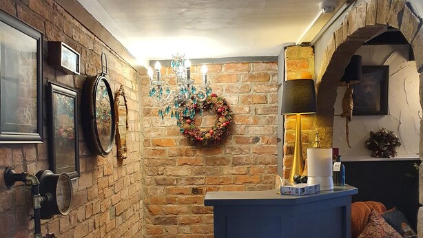 Een gezellige kamer met een bakstenen muur, een open haard, een blauw aanrecht en een decoratieve krans.