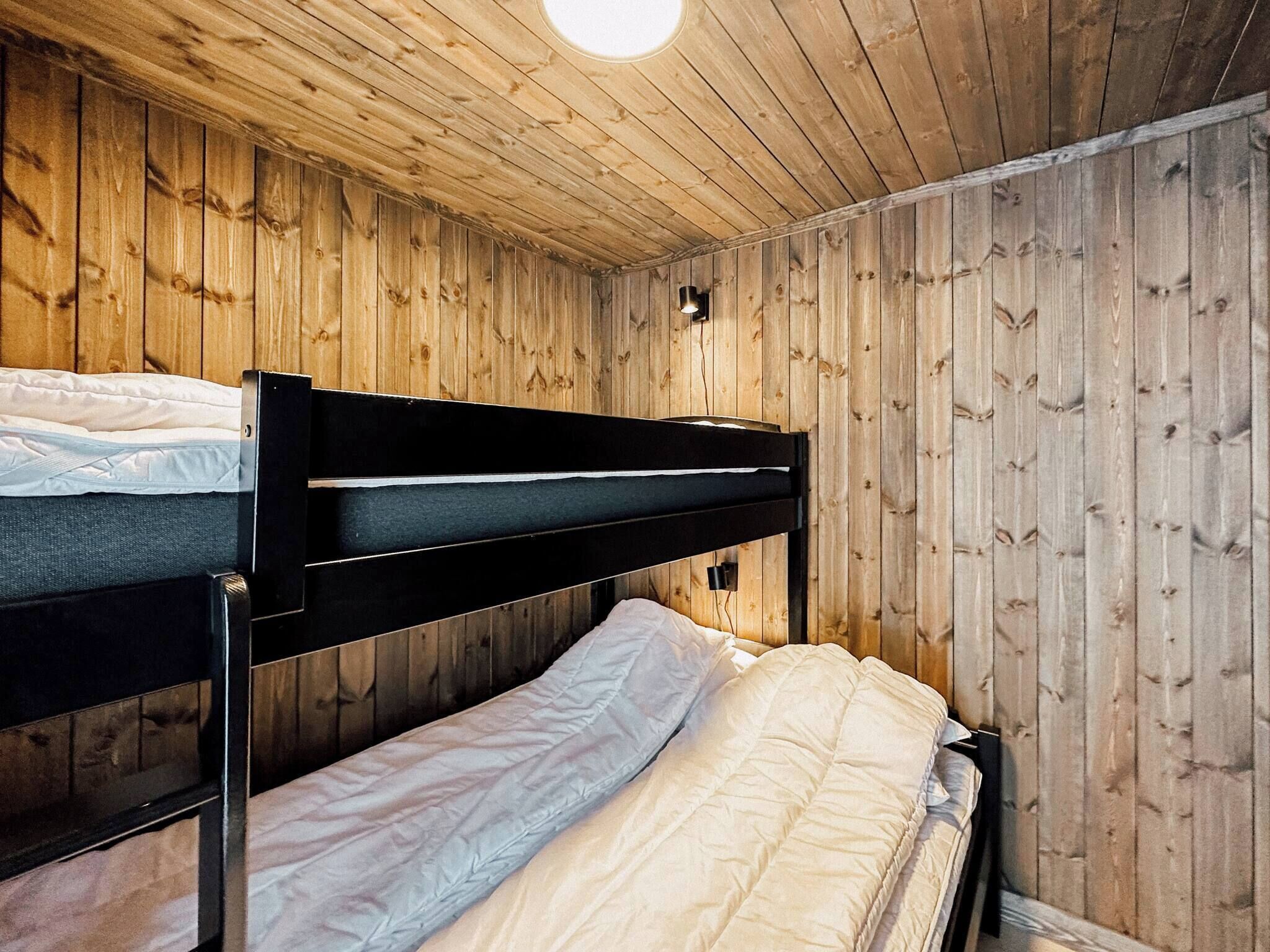 Ein Schlafraum mit Etagenbetten, Holzwänden und einer Deckenleuchte.
