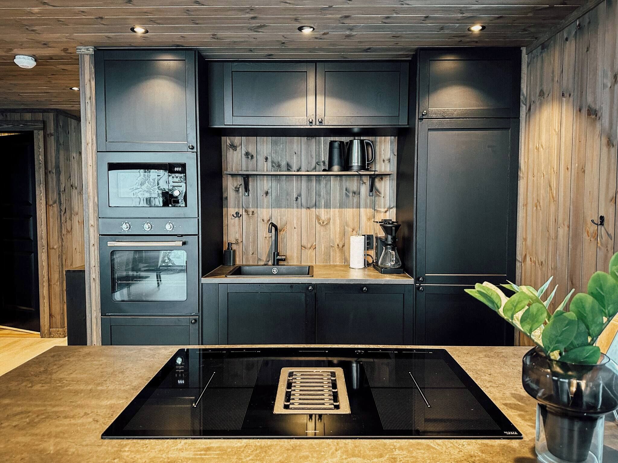 A modern kitchen with built-in appliances, a central island, and wooden paneling.
