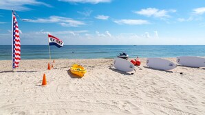 Ein Strand mit einer Flagge, einem Kajak und Surfbrettern.