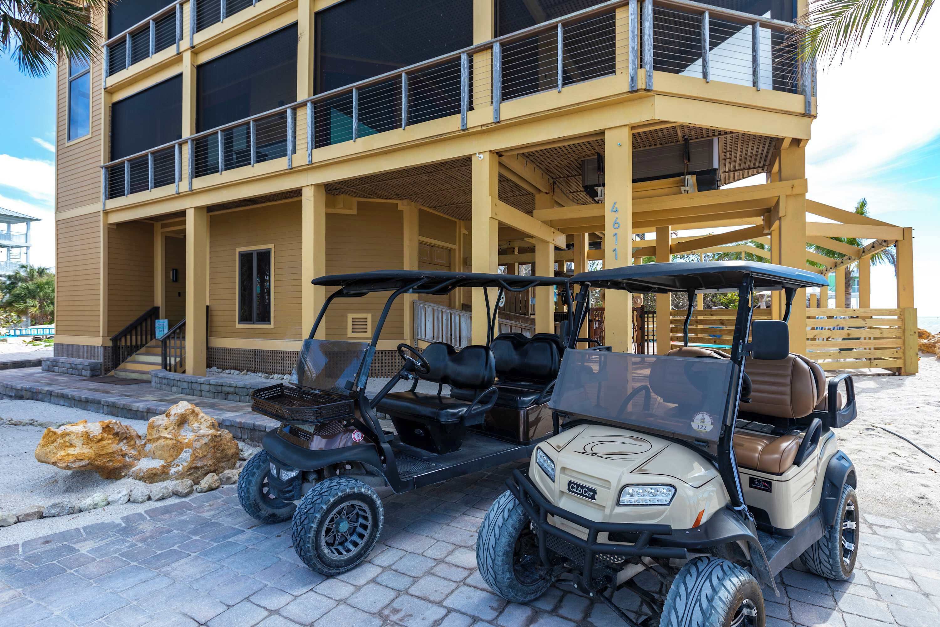 Een golfkarretje geparkeerd voor een gebouw met een balkon en een trap die naar de ingang leidt.