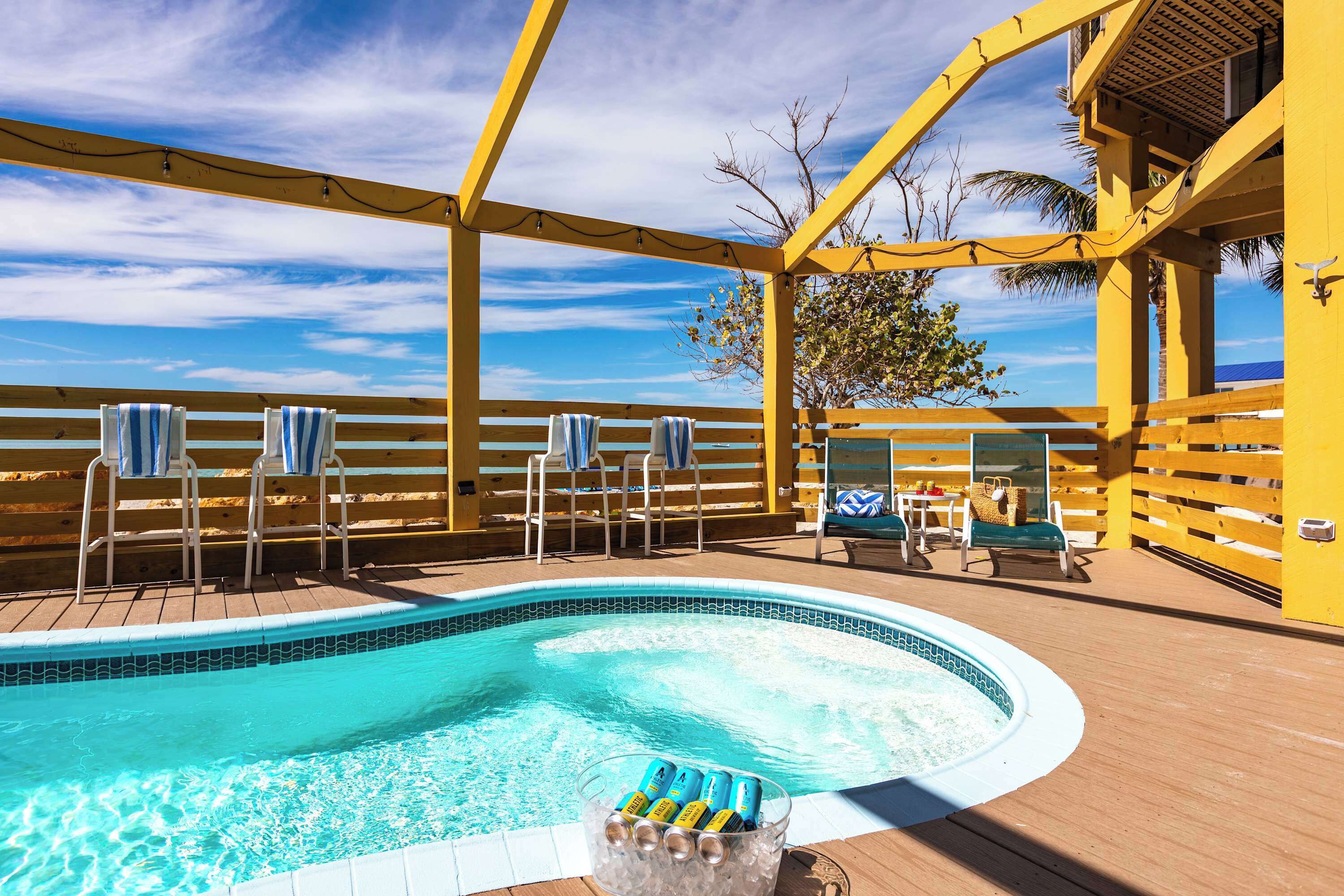 Un espace piscine équipé d’un jacuzzi, de chaises longues et de parasols.