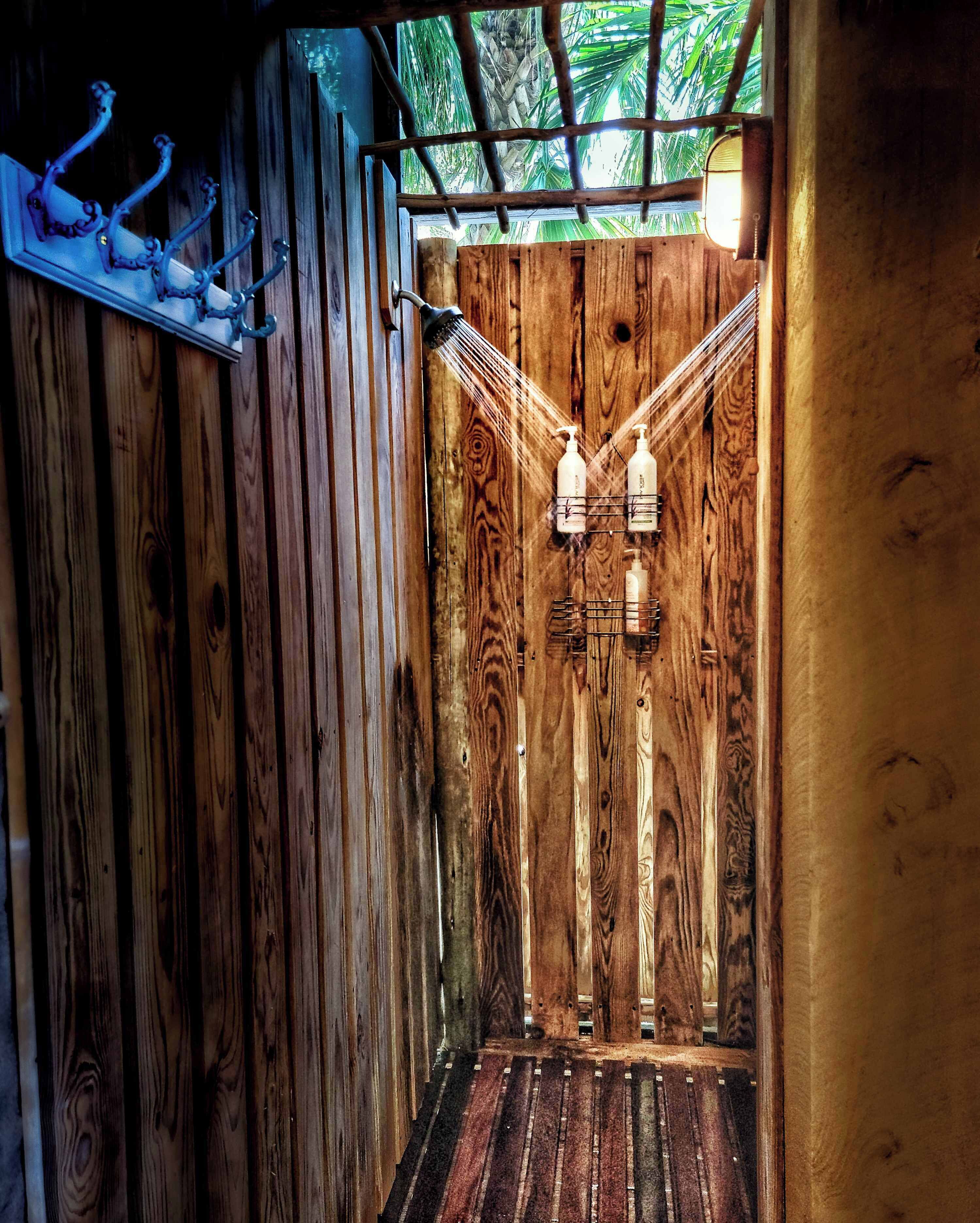A wooden interior with a sloped ceiling, a wooden floor, and a wall-mounted rack holding bottles.