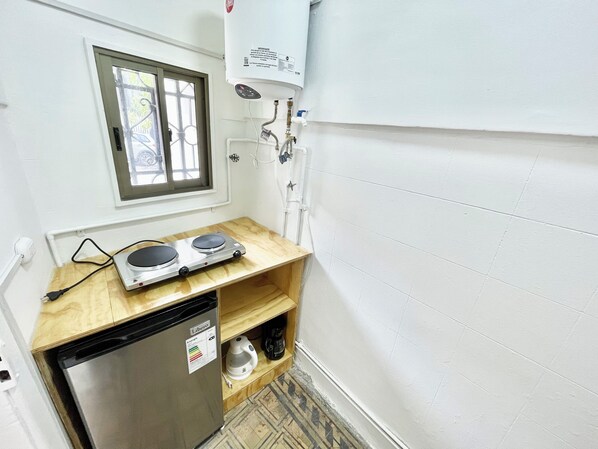 Una cocina compacta con refrigerador integrado, una pequeña encimera y un ventanal.