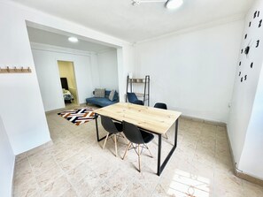 Una habitación moderna y luminosa con una mesa de comedor de madera, sillas negras, un sofá azul y una alfombra estampada.