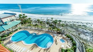 Ein Resort mit großem Pool, Liegestühlen und Blick auf Strand und Meer.