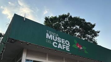 Een groen bord met de tekst 'TIENDA MUSEO DEL CAFÉ' en een afbeelding van een koffieplant.