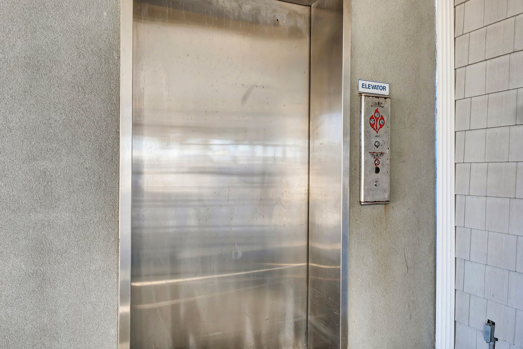 An elevator with a metallic door and a sign indicating its presence.