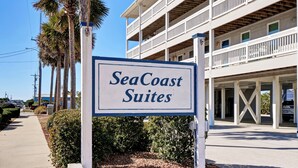 A sign for SeaCoast Suites with a multi-story building in the background. - Perfect Surf City Stay: Walk to Beach, Dining, & Fun (Surf City)