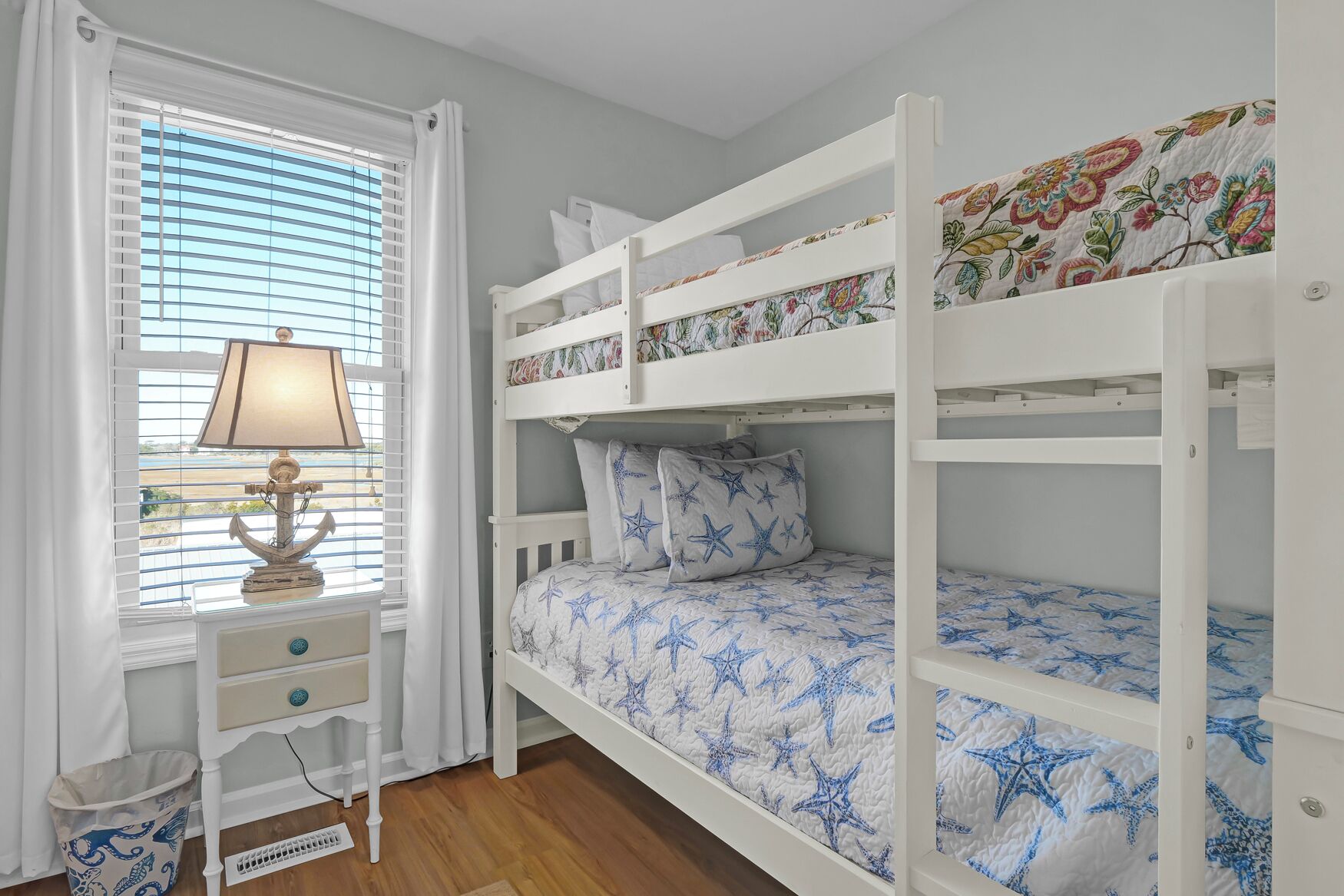 A child's bedroom with bunk beds, a desk, and a window with blinds.