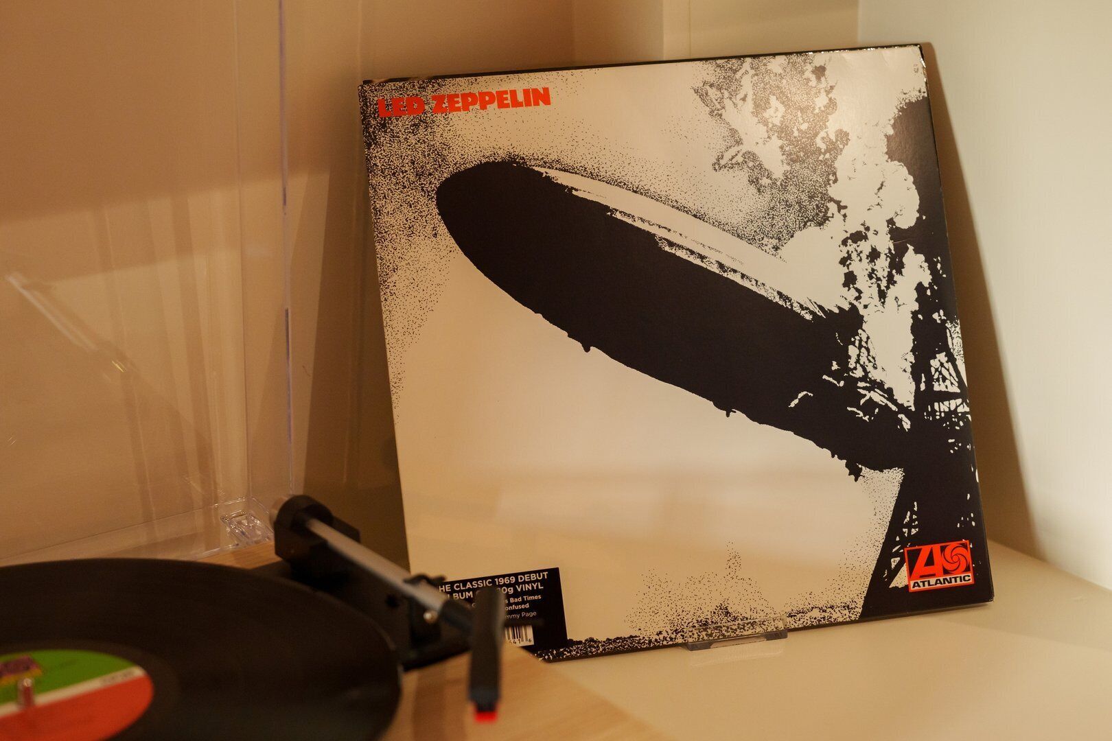A vinyl record by Led Zeppelin with a distinctive artwork, placed on a shelf next to a turntable.