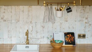 Une cuisine avec un évier blanc, un plan de travail en bois et un revêtement mural rustique.